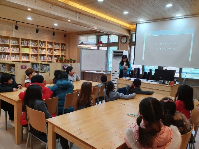 초등학생들이 전면을 향해 있으며, 담당자가 교육을 진행하고 있습니다.