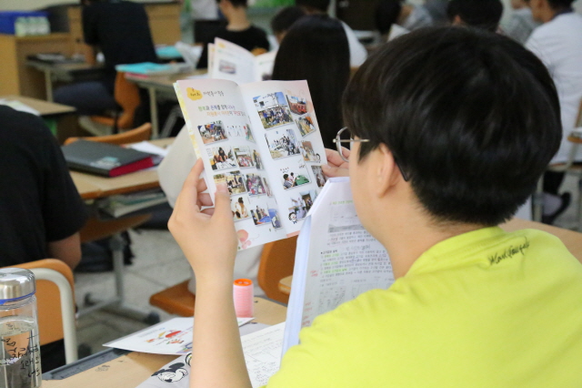 한 학생이 배포된 책자를 보며 자원봉사자 교육을 받고 있는 사진입니다. 