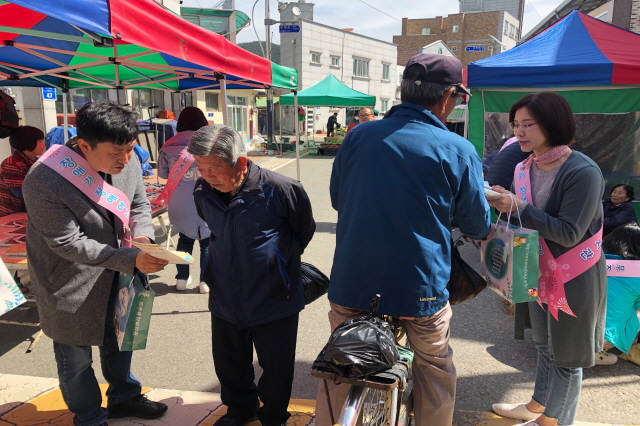   무주시장에서 지역주민에게 캠페인 홍보를 하고 있습니다. 